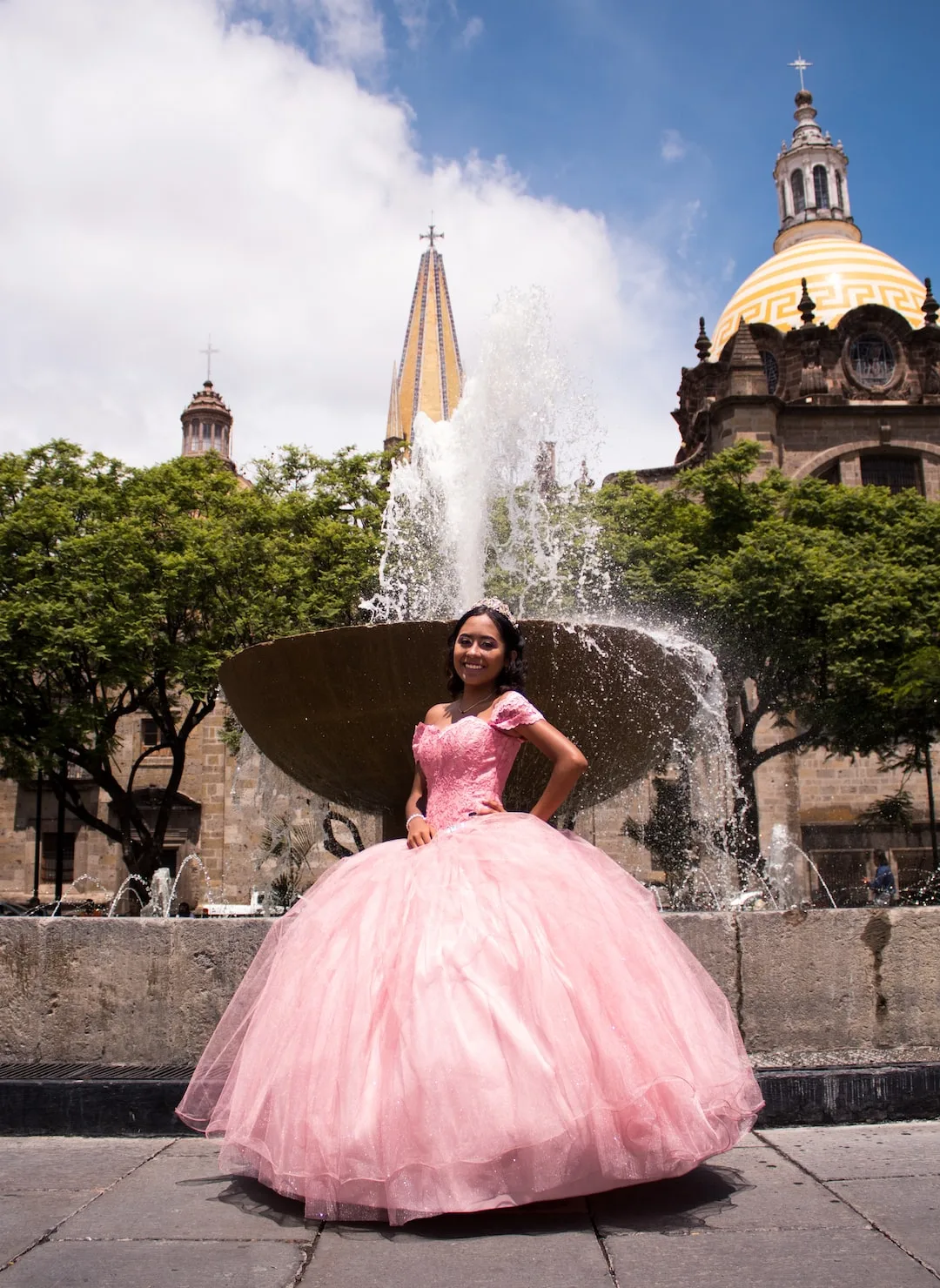 Pink ballgown by an outdoor cathedral fountain