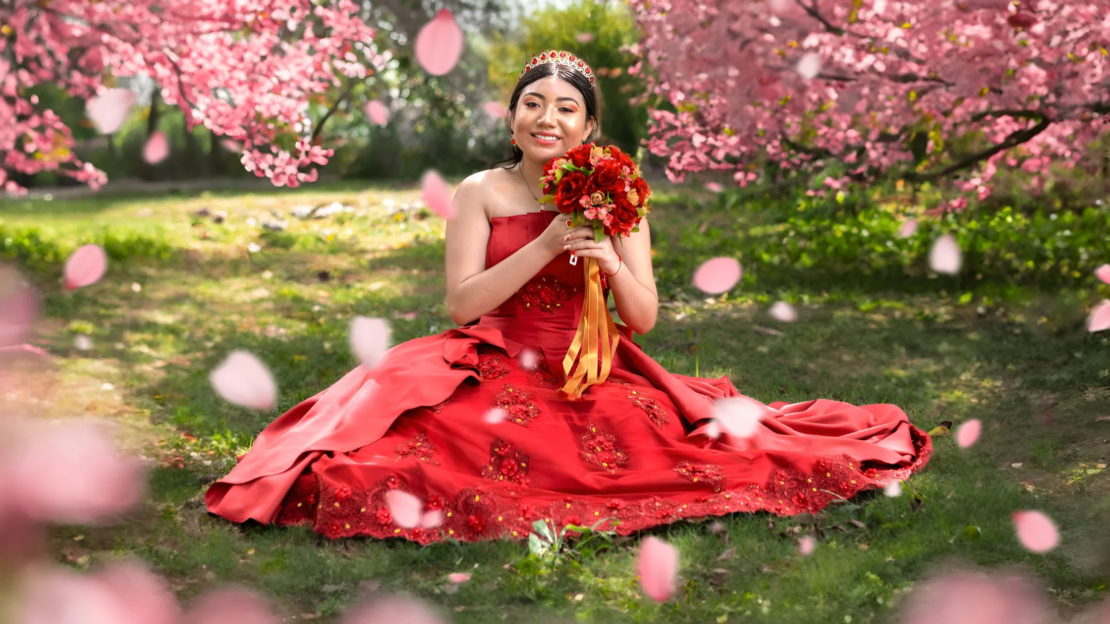 Red ballgown with cherry blossom petals in garden