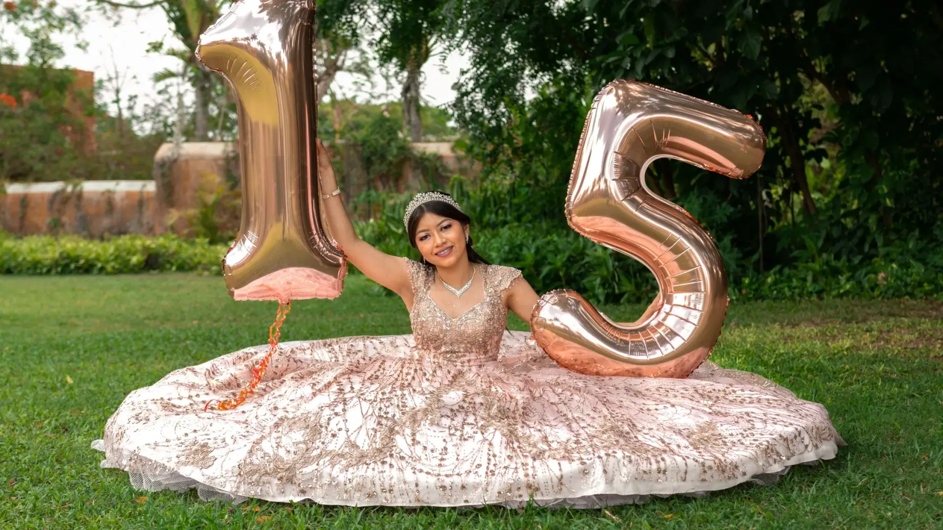 Quinceañera in rose-gold ballgown with balloons in a garden