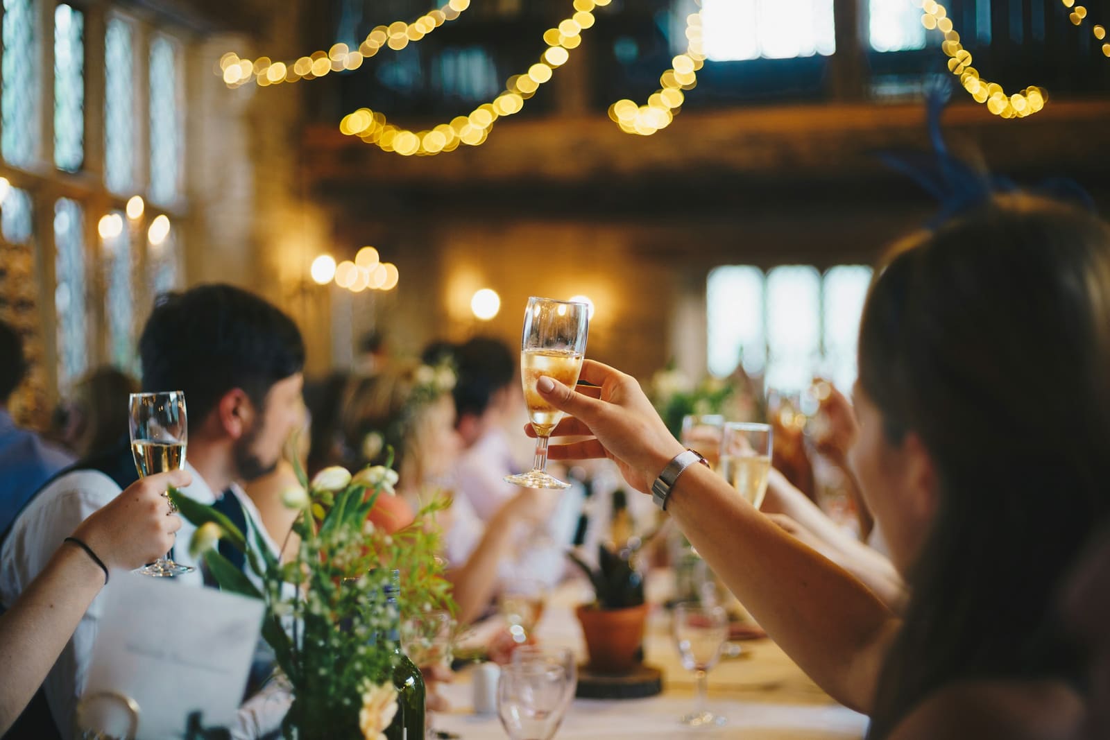 Champagne toast under warm string lights at a refined corporate celebration