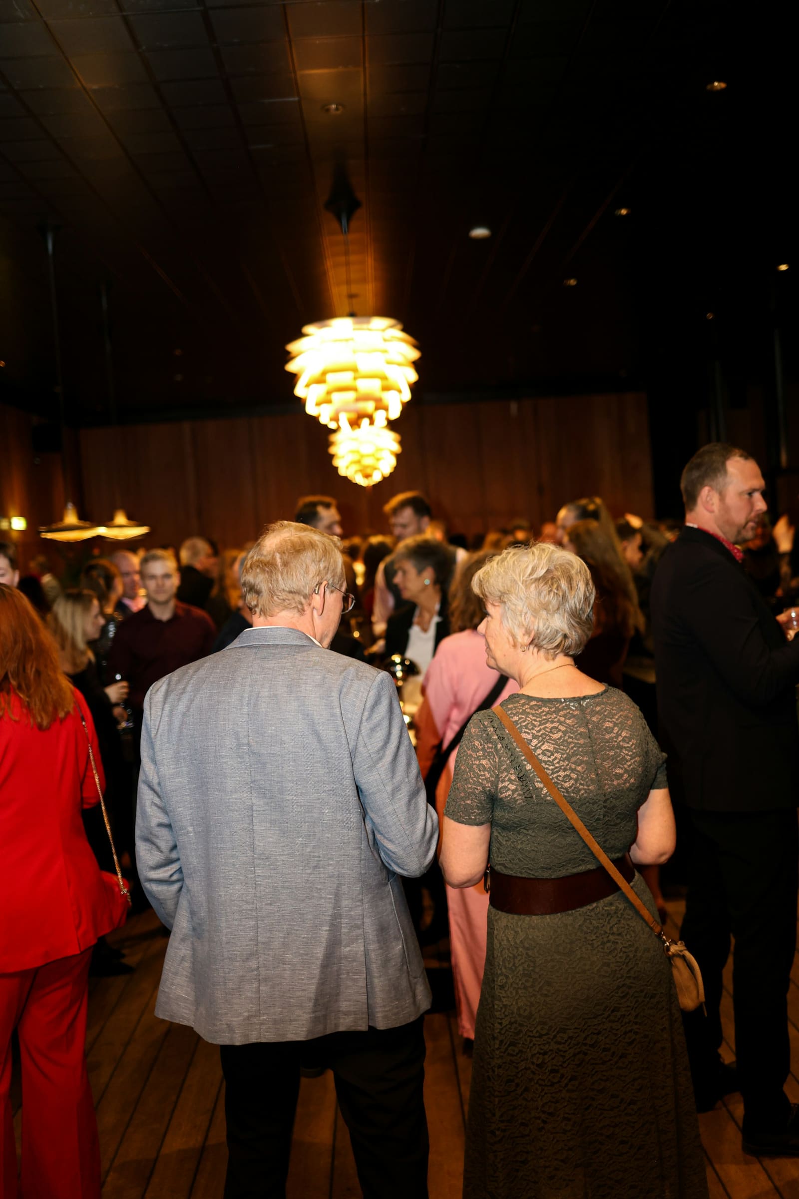 Guests mingling under an ornate sculptural chandelier at an evening reception