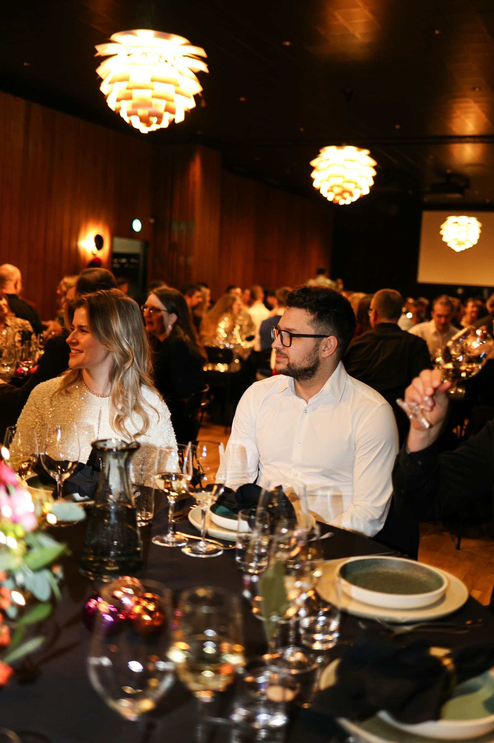 Guests seated at a candlelit gala dinner with statement chandeliers and refined place settings