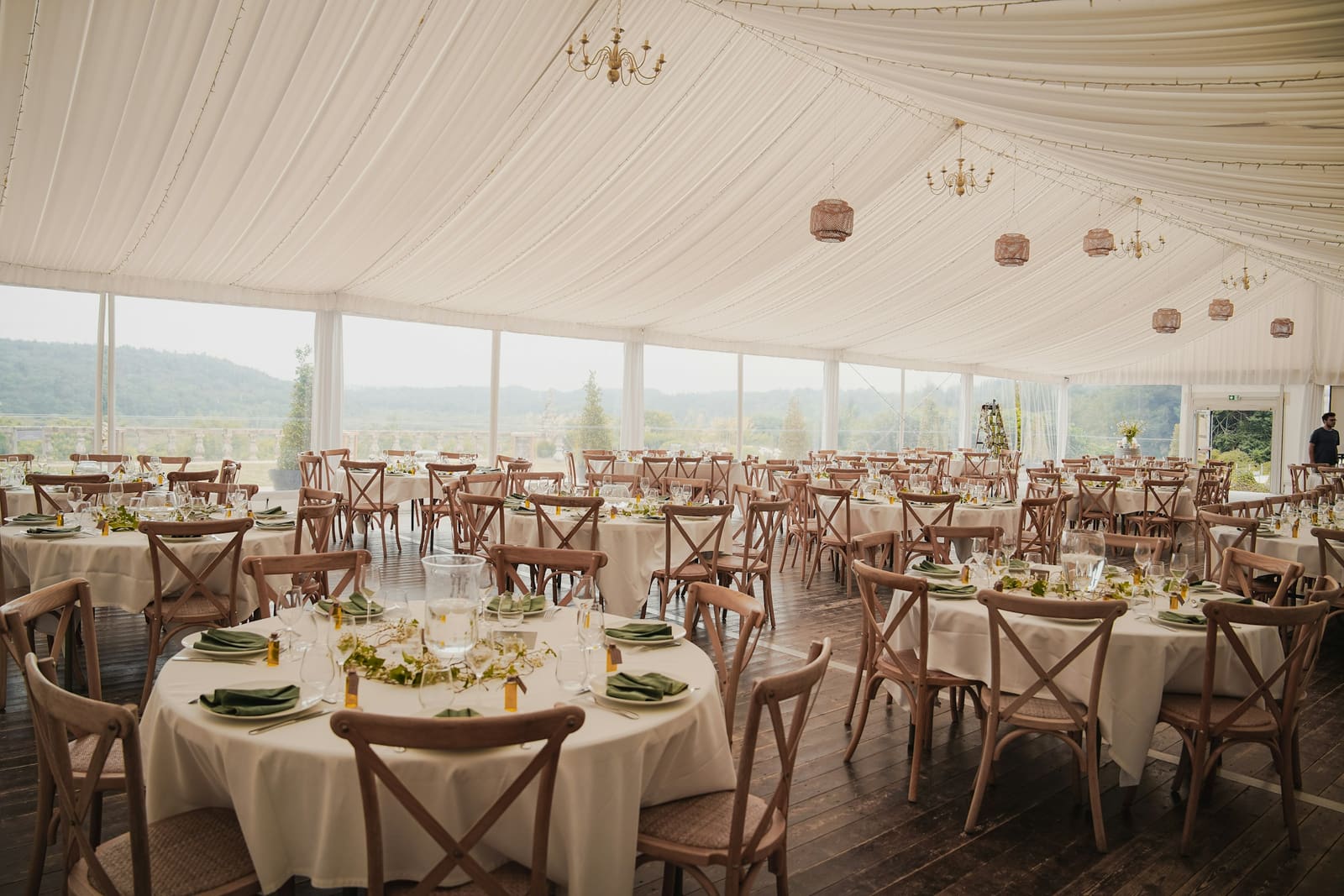 Elegant tented reception venue with draped ceiling, chiavari chairs and round tables