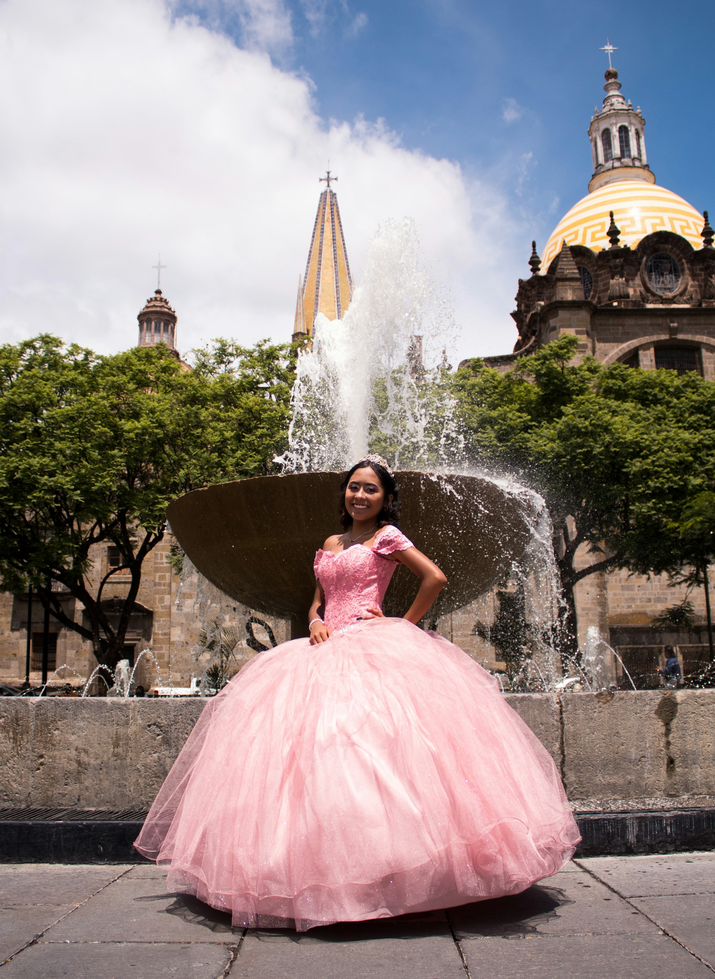 Quinceañera in pink dress standing on a fountain (Unsplash · @badomar)