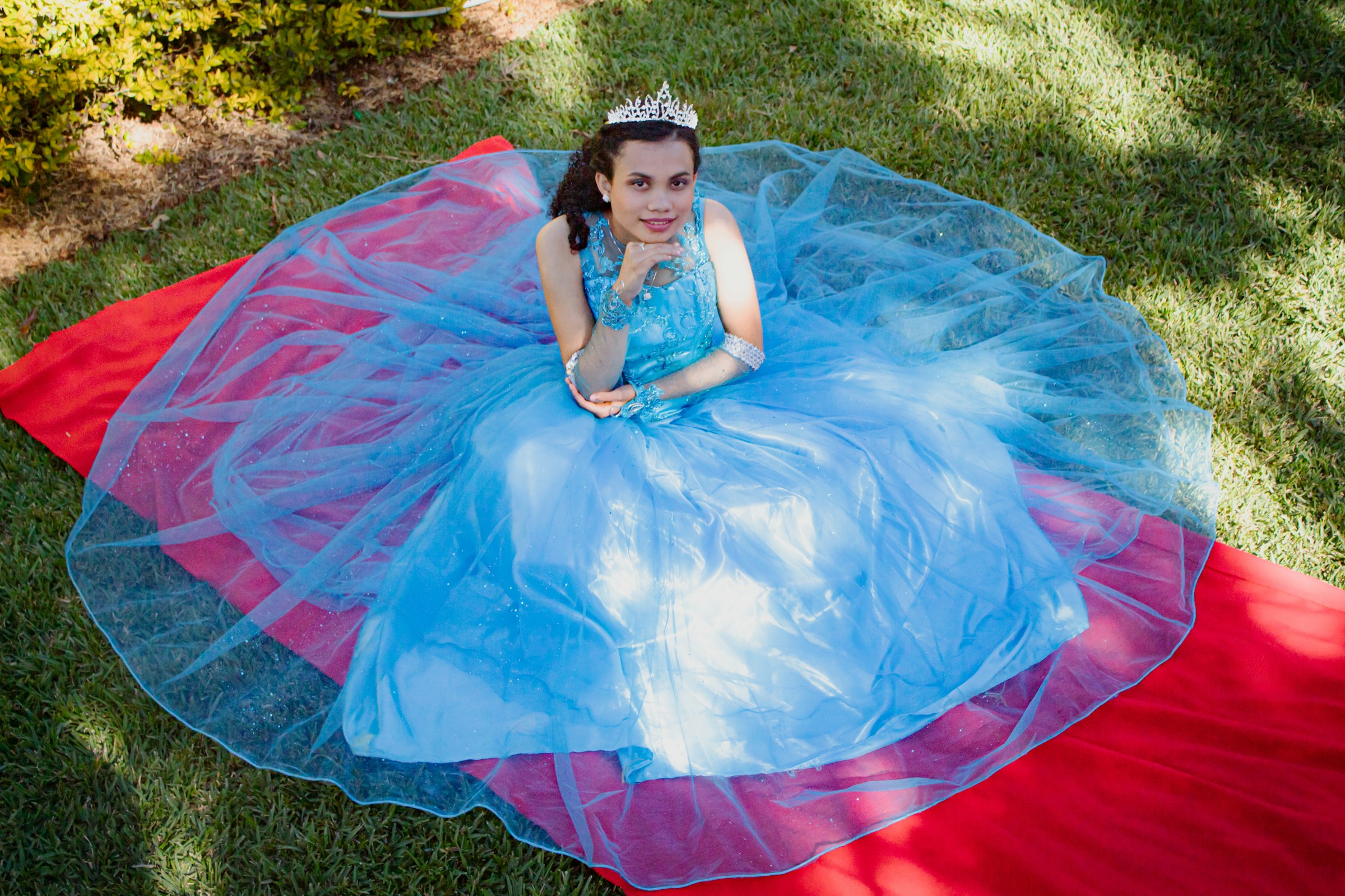Quinceañera in blue and pink dress on a vibrant blanket (Unsplash · @pablogt)