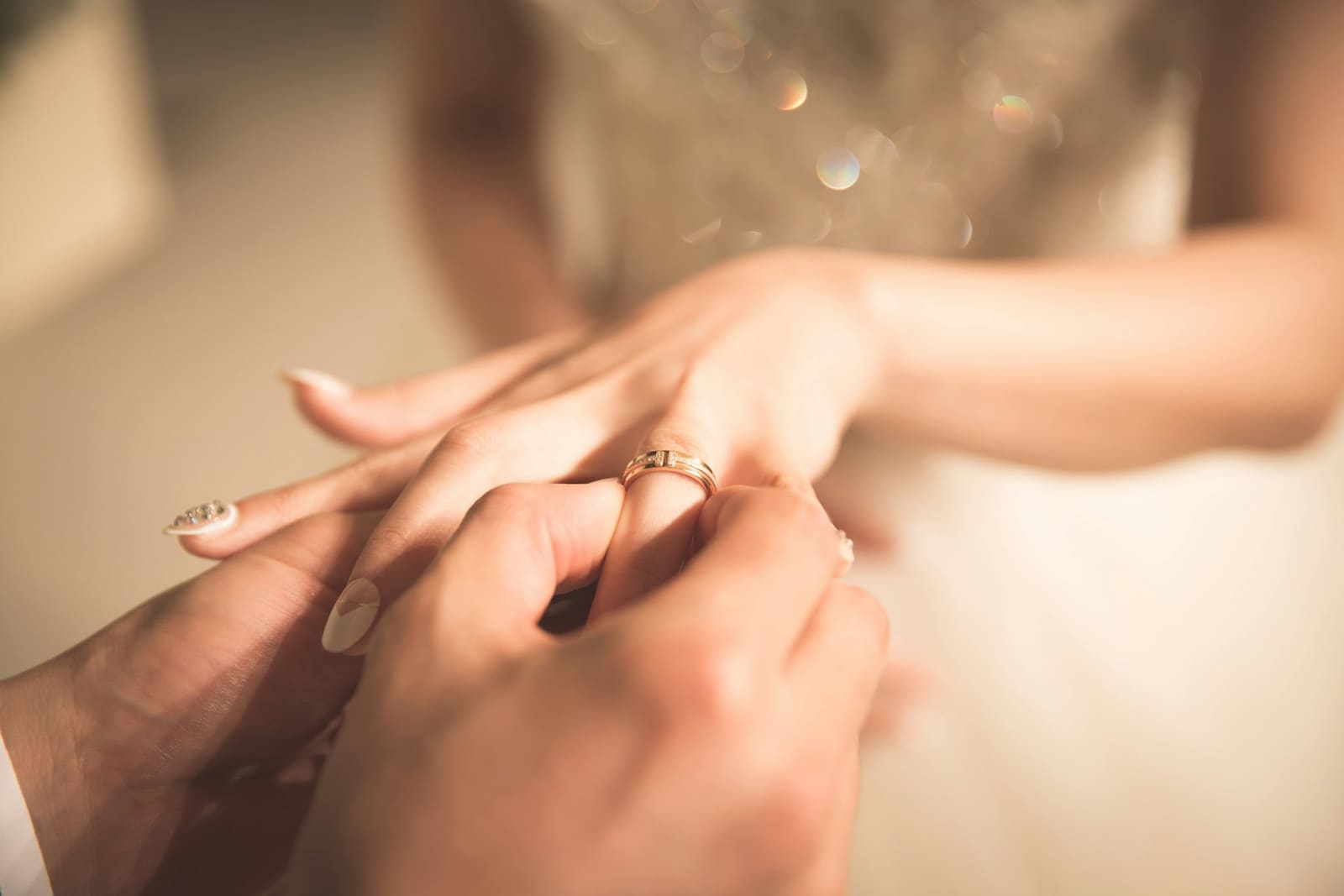 Close-up of the groom slipping a gold band onto the bride's finger during the ring exchange